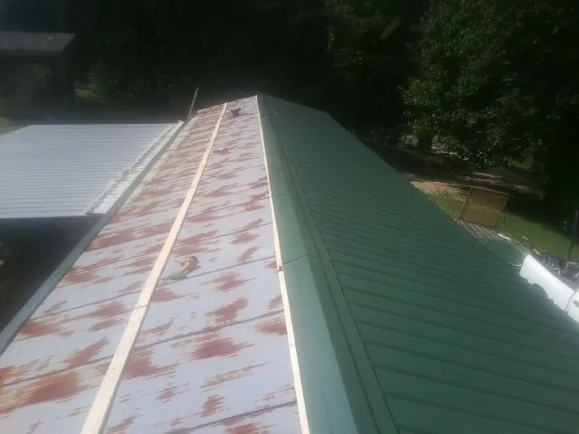 Old rusted panels beside newly installed green metal roofing — Wind Damage Roof Repair by Roofing Brothers in Kamiah