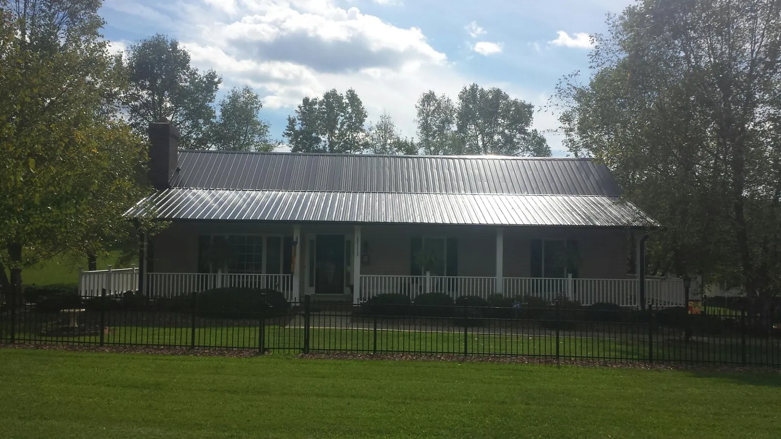 Gray metal roof on a brick ranch with a full width front porch — Gutter Guard Installation work by our crew in Kamiah