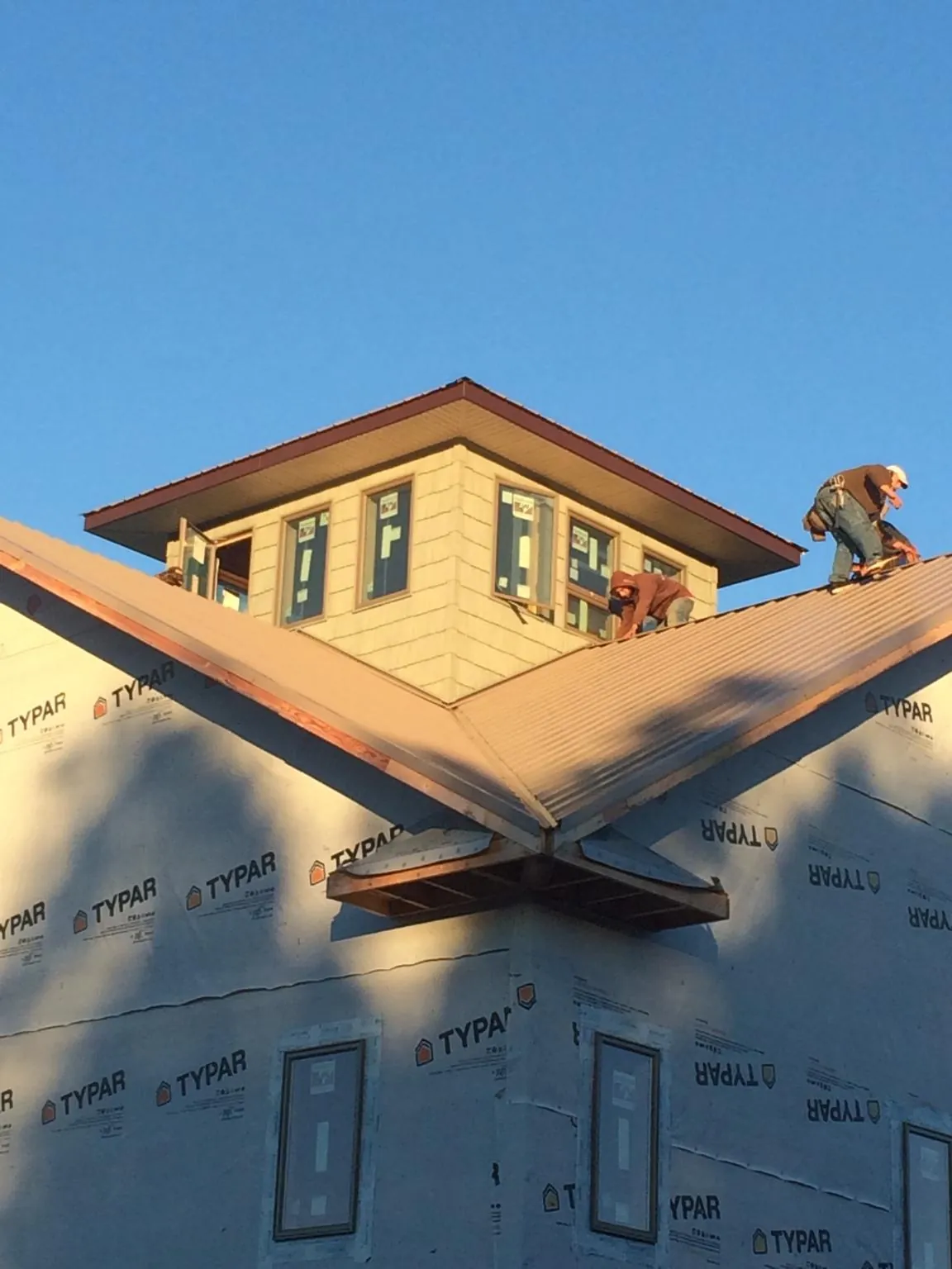 Roofers working around a rooftop cupola on a new metal roof at sunset — Roof Waterproofing in Kamiah by Roofing Brothers